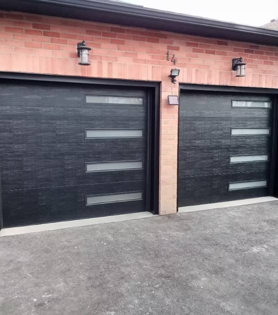 Two modern black flush-panel garage doors with frosted glass strips on a brick double garage